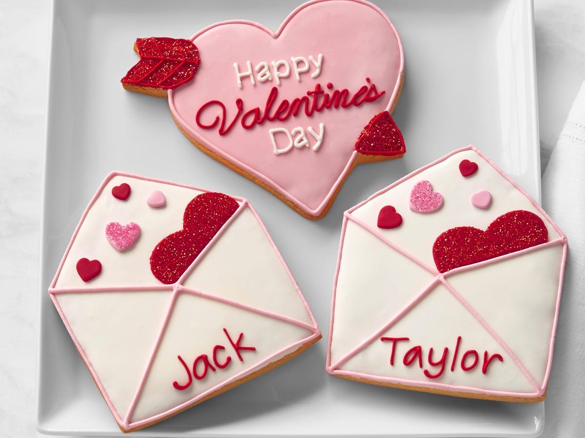 Set of three personalized Valentine's Day cookies, one shaped like heart and two shaped like love letter with the names "Jack" and "Taylor" written on them in icing.