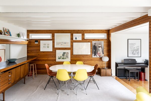 Pine wall panelling wraps around the main living spaces, creating an immediate feeling of warmth and texture. Soft carpet underfoot in the dining area adds a subtle contrast.