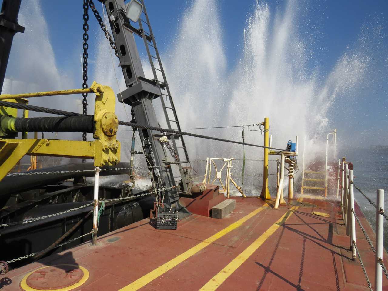 ship deck built with heavy equipment with water shooting into the air over the deck