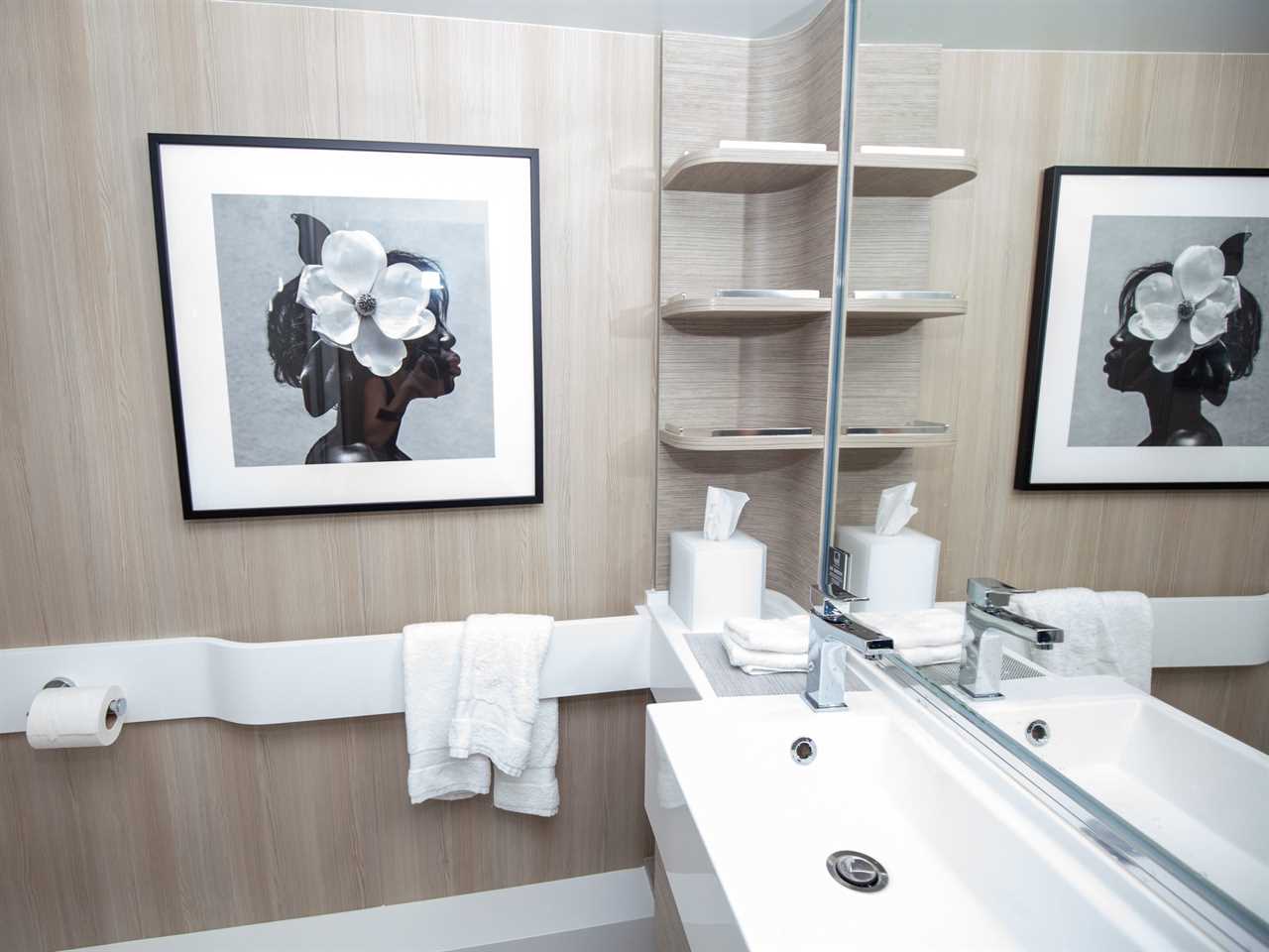 a bathroom with a sink, shelves, and towels