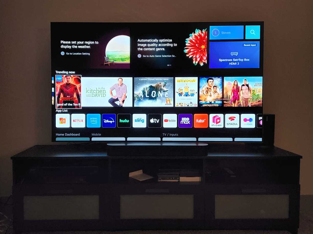 The LG webOS menu pictured on an LG G2 OLED TV resting on an entertainment console.