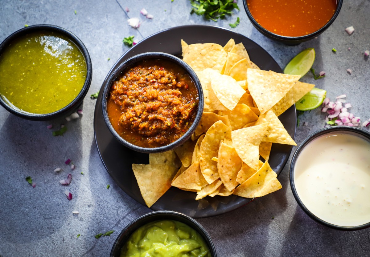 chips, salsa, guacamole, and queso on table