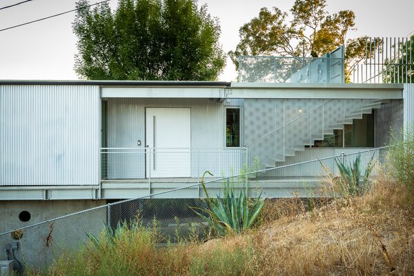 Upon arrival, steps descend to the main entrance, which opens to spacious living areas.