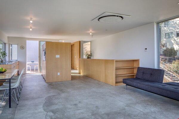 Polished concrete flooring enhances the home's sleek, modern aesthetic, while also complementing the bespoke wooden details found throughout the living area and kitchen.