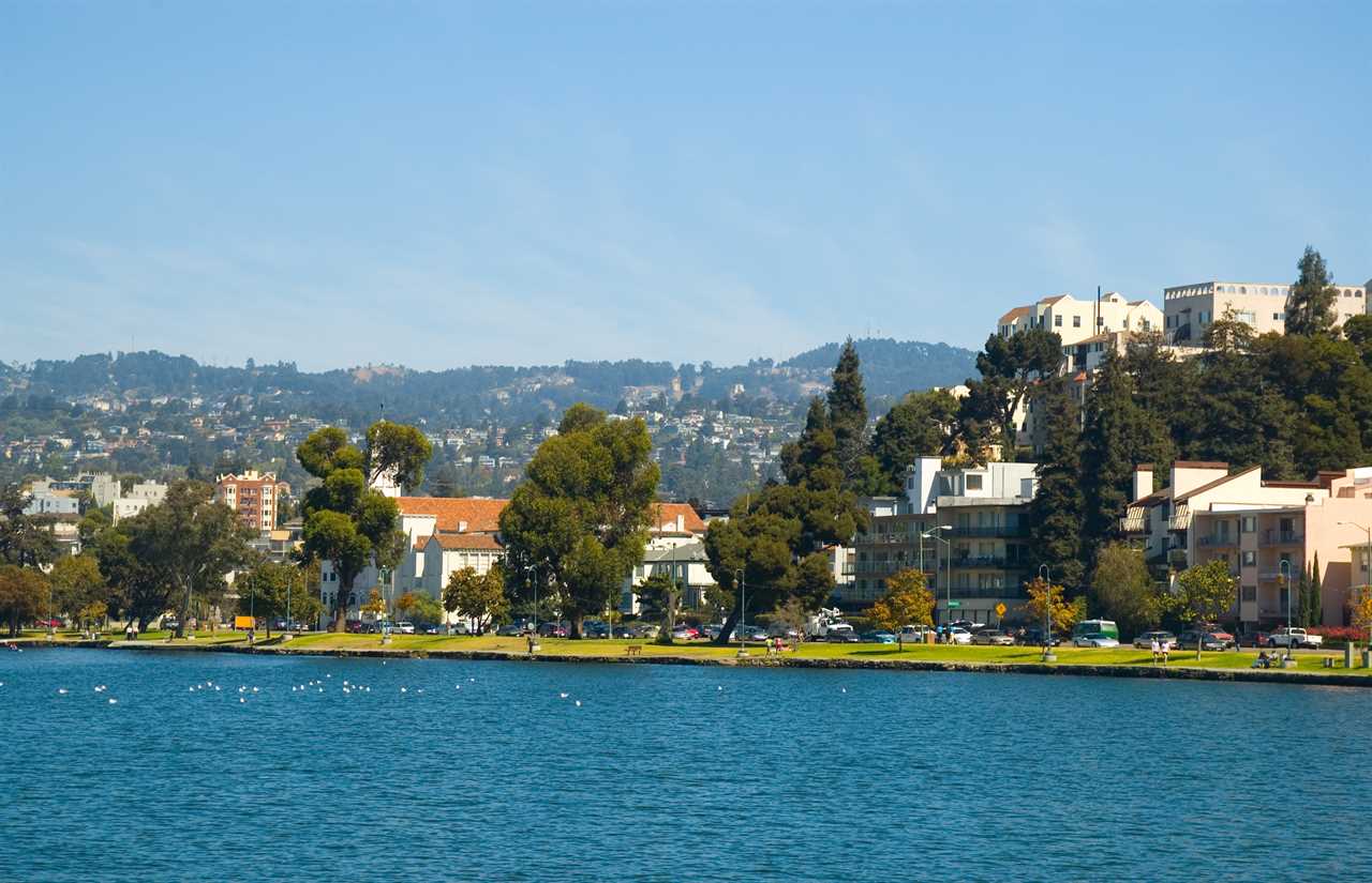 ake Merritt, park, people walking in the park area, and apartment buildings, trees, and the oakland / berkeley hills in the background.