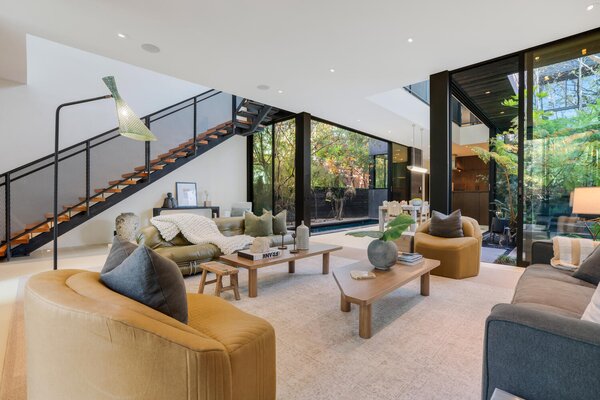 Inside, black-framed glazing pops against the crisp white walls and ceilings. All of the main living spaces are located on the lower level, with the dining area just steps from the kitchen.