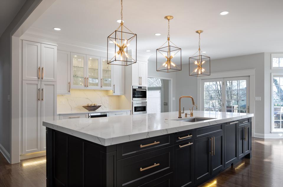 Transitional kitchen with black and white cabinets, marble look top, three pendants. 