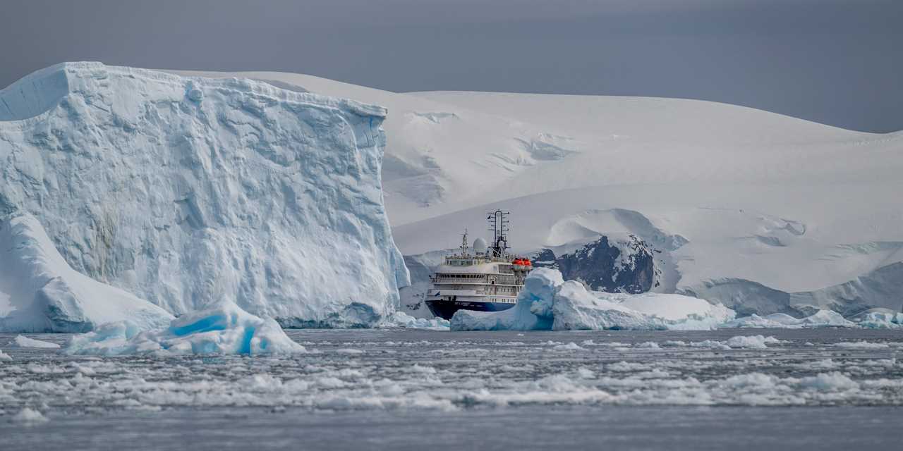 A cruise ship is pictured next to a small ice berg.