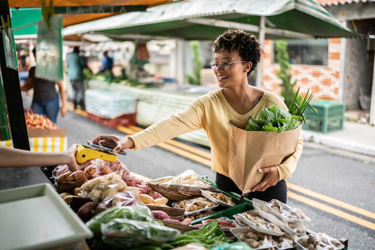 A woman paying for produce at a street market