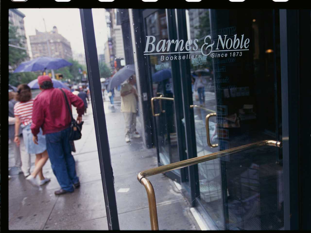 Glass door to Barnes & Noble book store with people on sidewalk behind