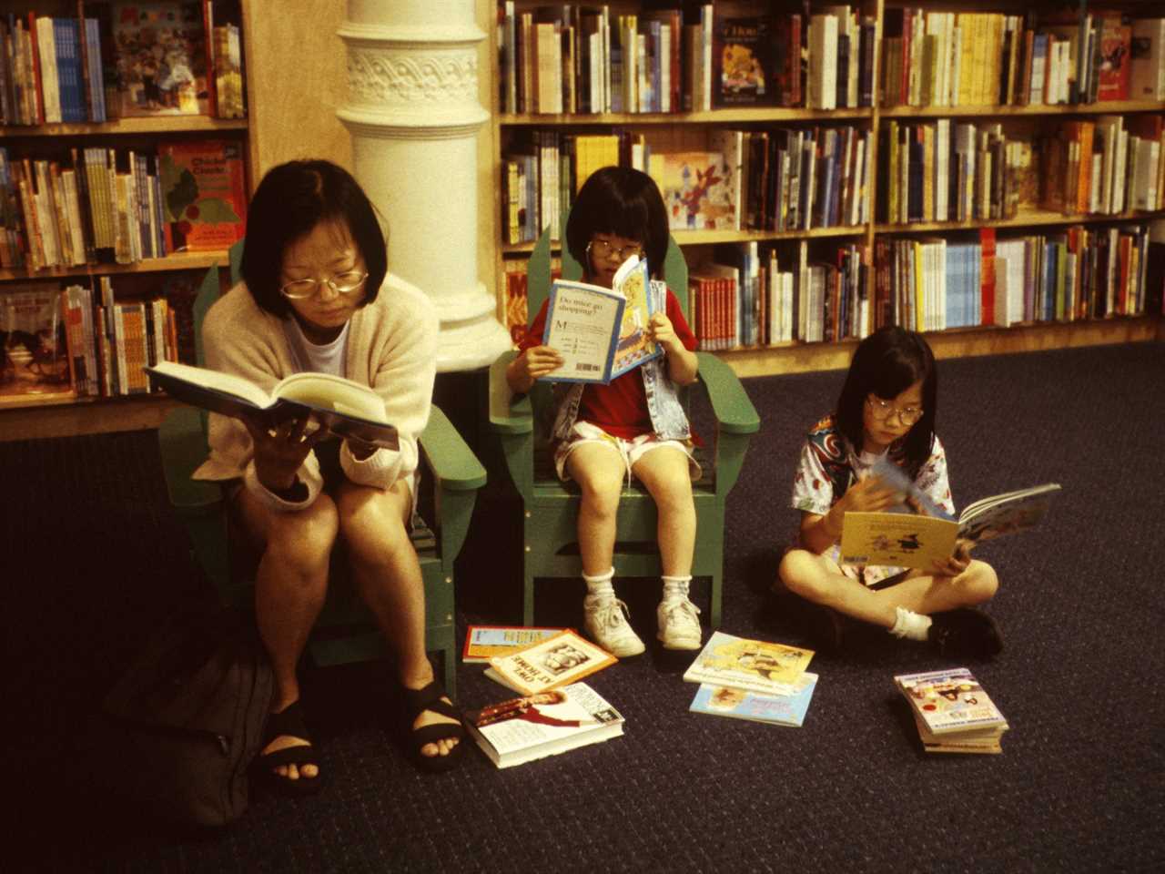 A mother and two daughters sit and read books at a Barnes & Noble store