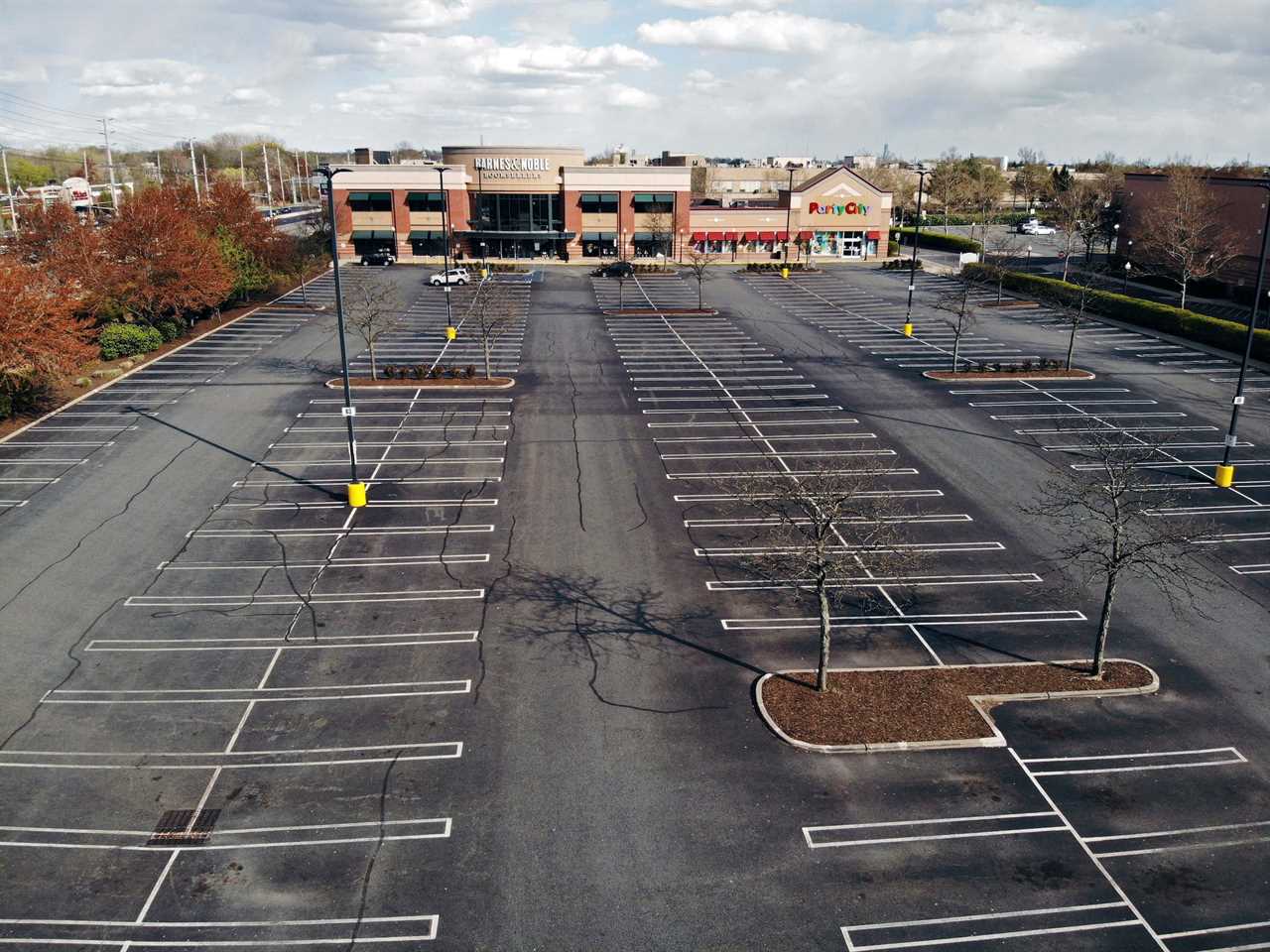 Aerial view of empty parking lot in front of Barnes & Noble and Party City stores during pandemic