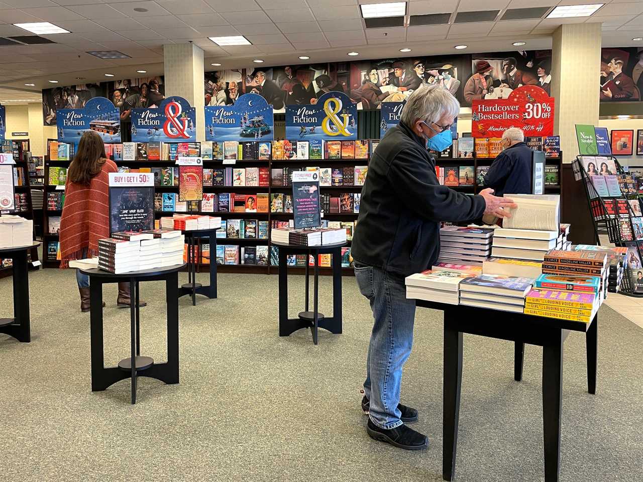 Man stands at table looking at books near other customers in Barnes & Noble