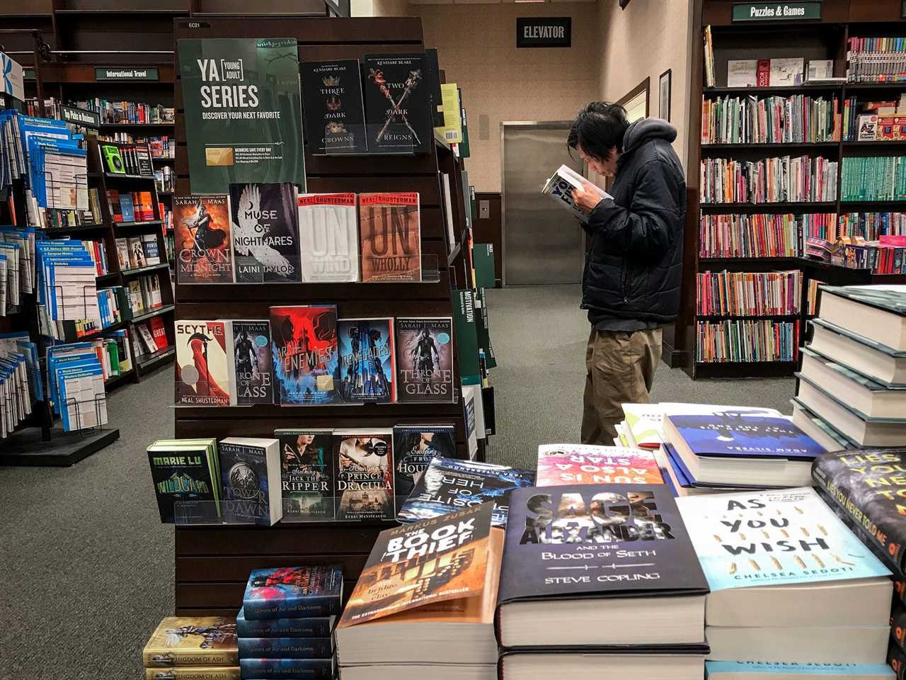 Man reads book closely in aisle of Barnes & Noble store