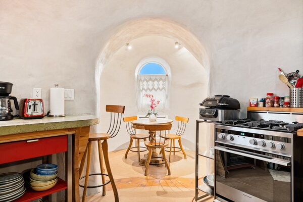 Inside, curved white walls and ceilings enhance the hobbit-like atmosphere. Located steps from the main living room is a spacious open kitchen, which includes a cozy breakfast nook.