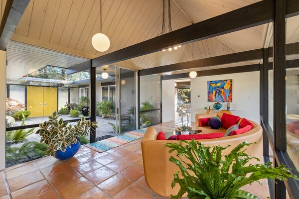 At the center of the home is a cozy, light-filled sitting area, where black exposed beams pop against the white cathedral-like ceilings. A remodeled kitchen awaits just steps away.