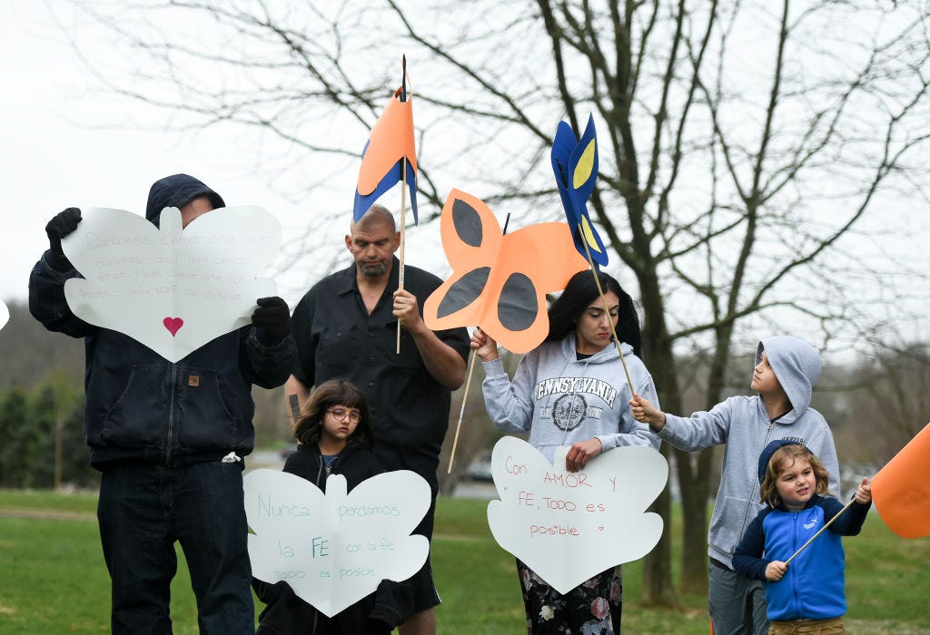 John Fetterman and Gisele Fetterman with their three children holding signs at a vigil