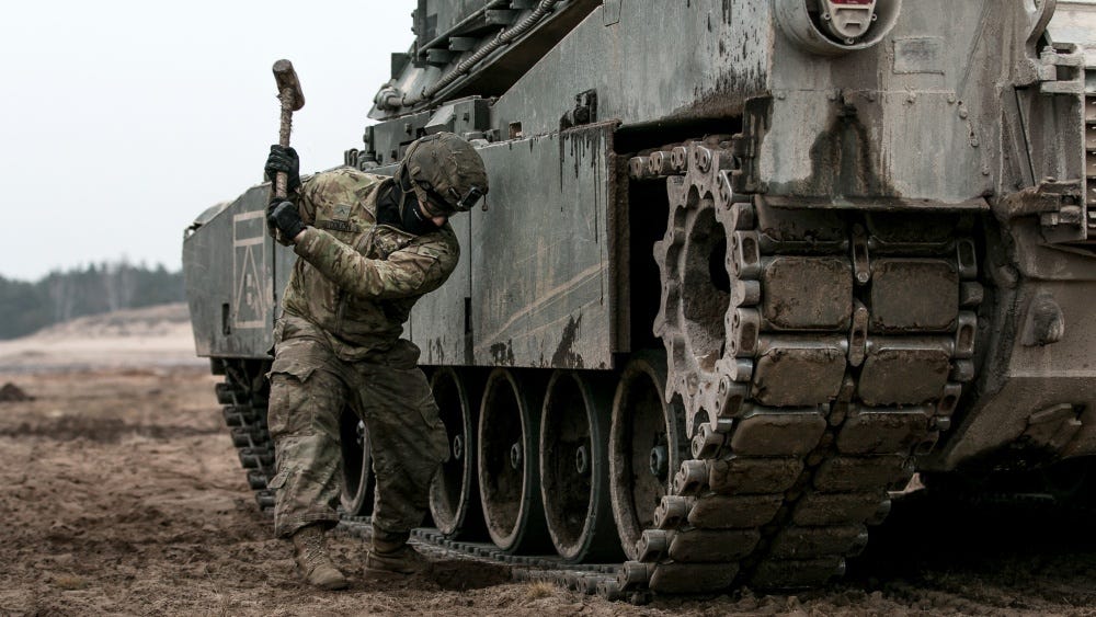 An armor crewmen performs maintenance on a M1 Abrams tank during a platoon combined arms live fire exercise