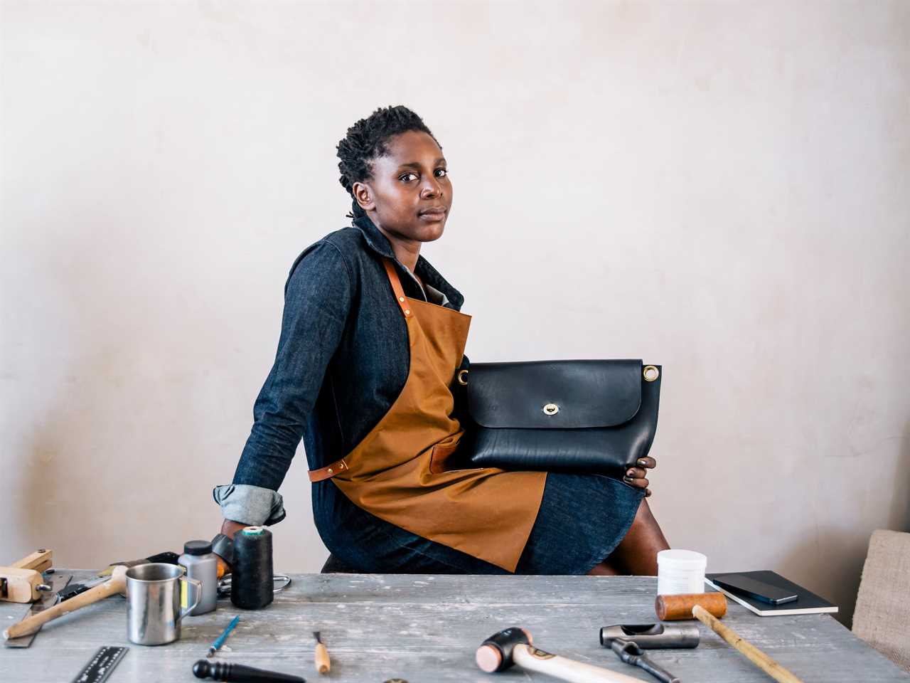 Portrait of a small business owner sitting behind her desk, with finished handbag