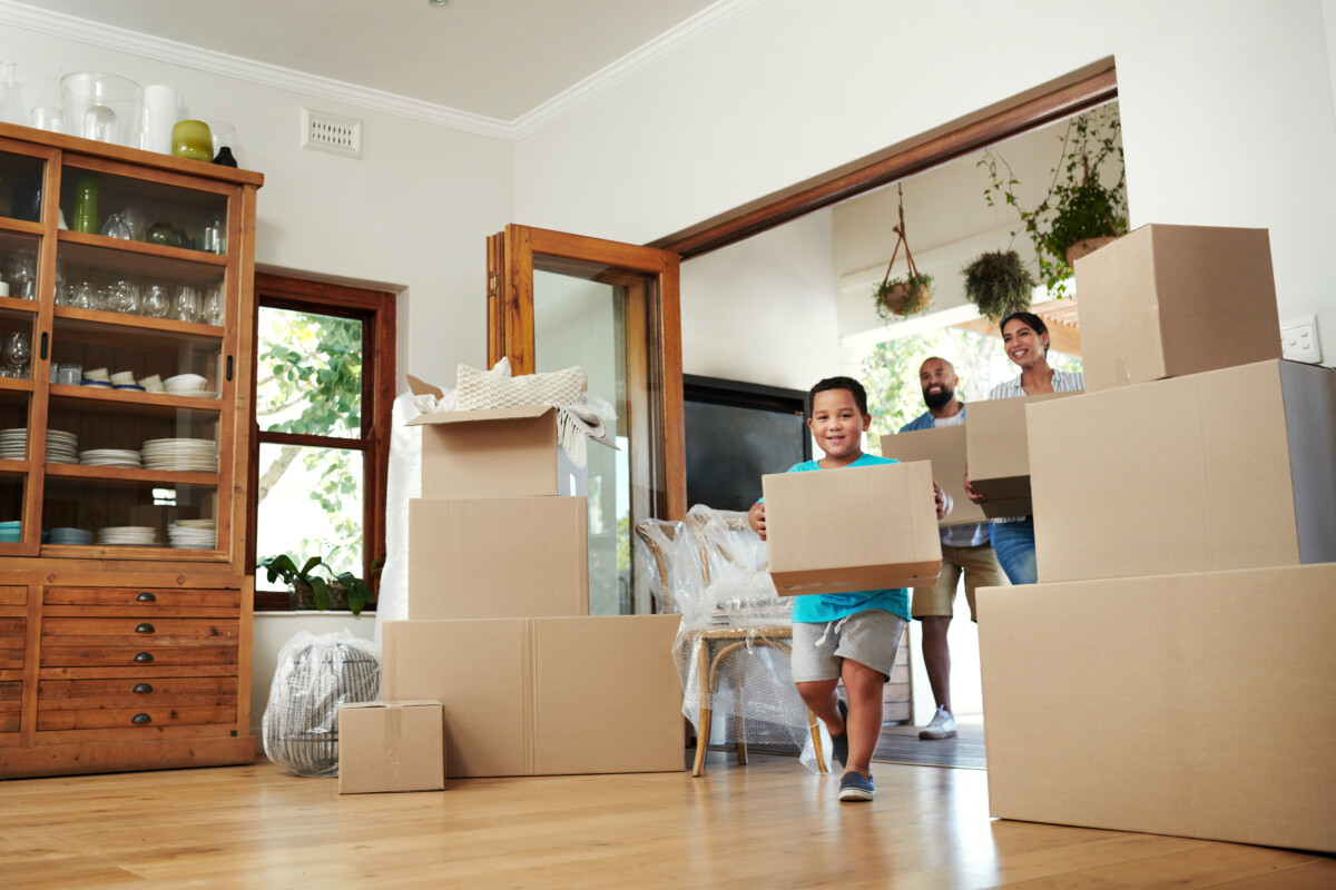 Shot of young family of three carrying moving boxes into their new home _ getty