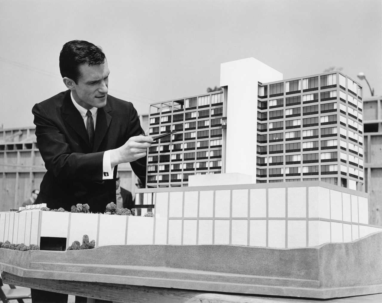 Playboy magazine founder Hugh Hefner poses for a portrait next to an architectural building model circa 1965 in Los Angeles, California.