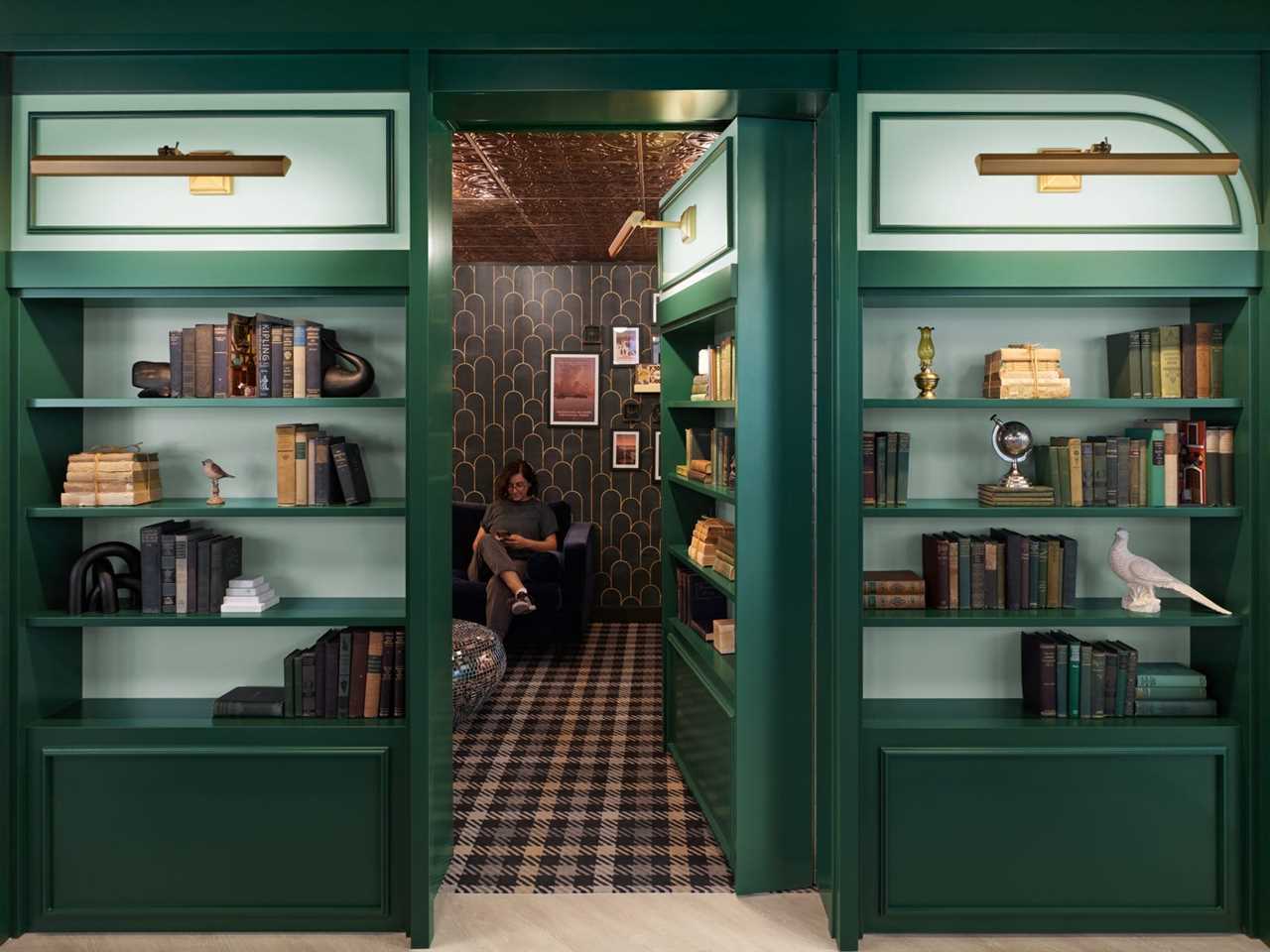 A speakeasy meeting room behind two bookcases.