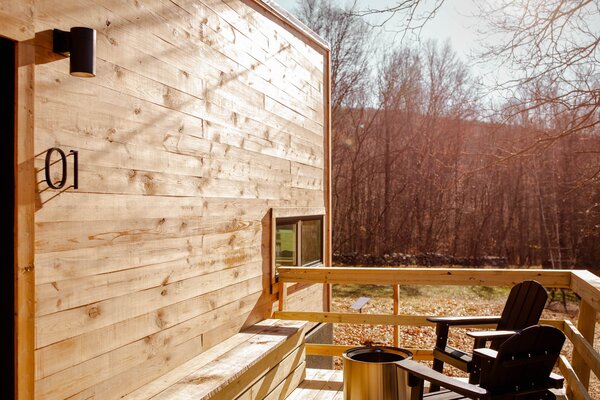 Set in the woods, the cabin is encircled by towering trees.