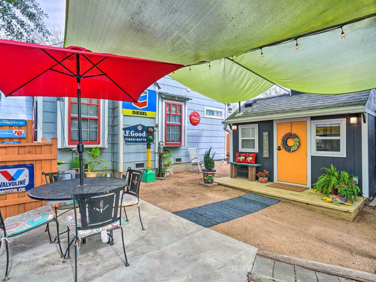 A red umbrella and table with four chairs outside the tiny home