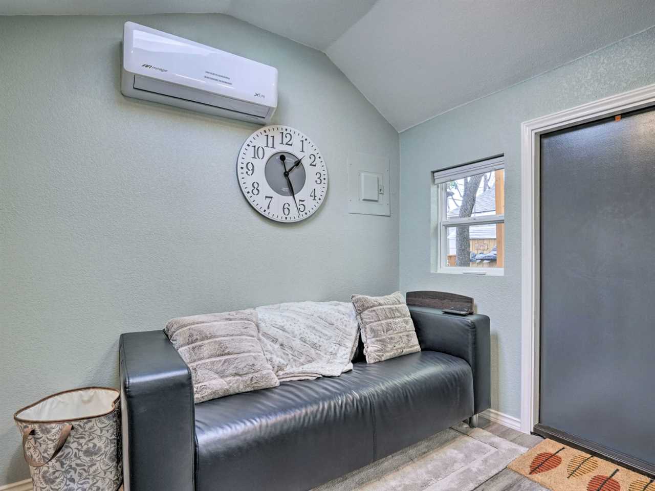 A pale blue wall and a black leather sofa in the entryway