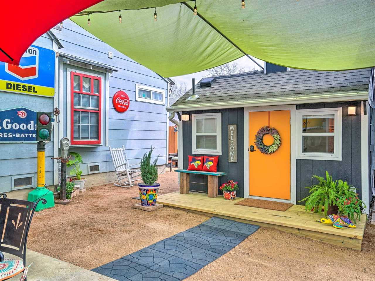 A quaint blue shed with a bright orange door with green tarp hanging overhead