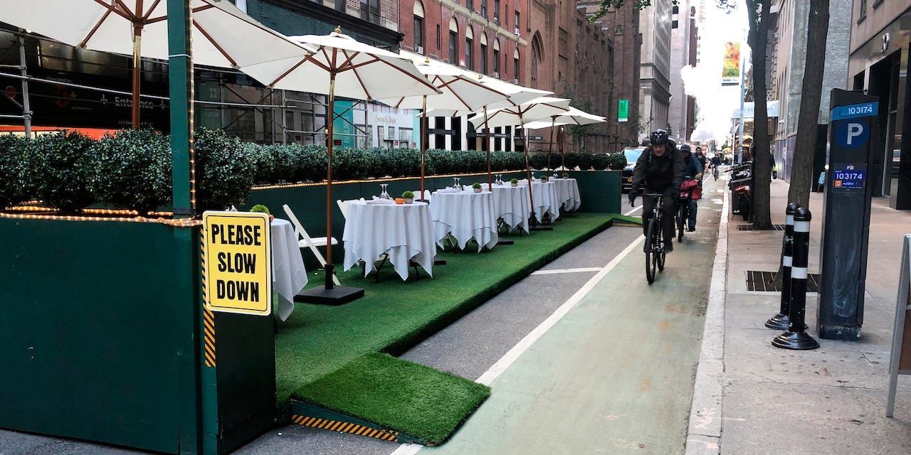 Cyclists ride by a restaurant's outdoor dining area in New York City.