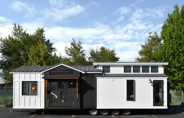 The tiny home on wheels that Tru Form Tiny designed and built for Judy and Dean Anderson is wrapped in white-painted pine and accented with ebony-stained cedar around the door.