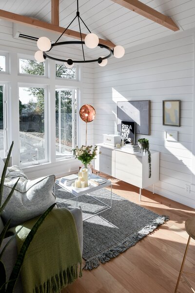 Expansive windows flood the living area, outfitted with hickory flooring and ceiling beams, with plenty of natural light.