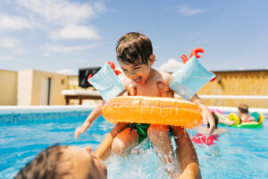 Little boy having fun with his father while swimming in the pool.