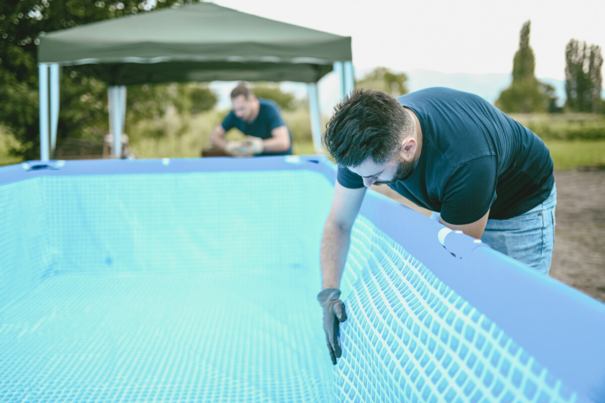 Pool owners scraping off debris and algae from the pool walls and pool floor