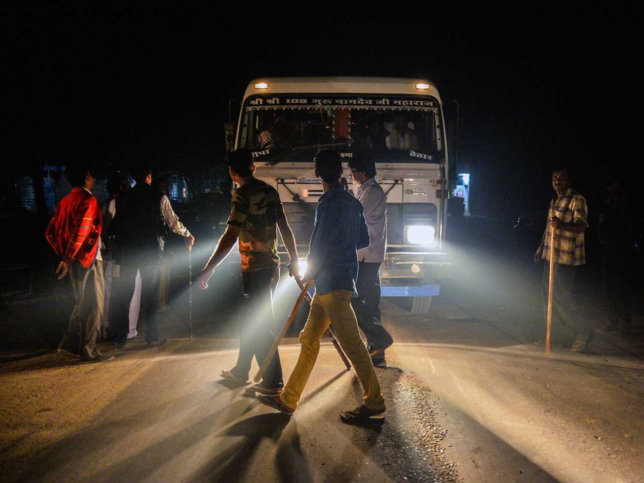 Volunteers for a vigilante group that enforced a ban on beef slaughtering are illuminated by headlights as they stand in front of a truck in India in 2015.