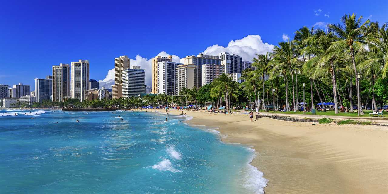 A view of Honolulu from the beach with buildings and palm trees