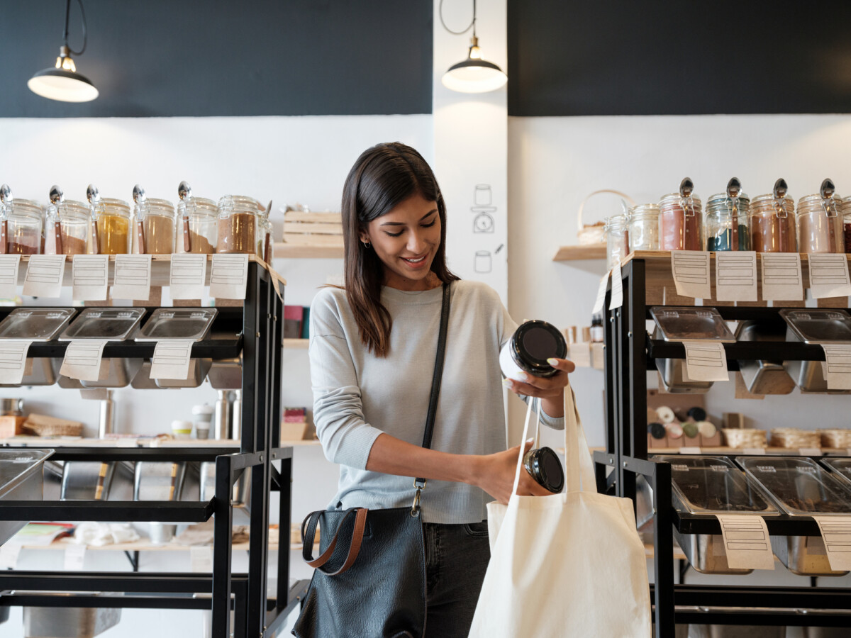 Young woman putting merchandise in reusable shopping bag