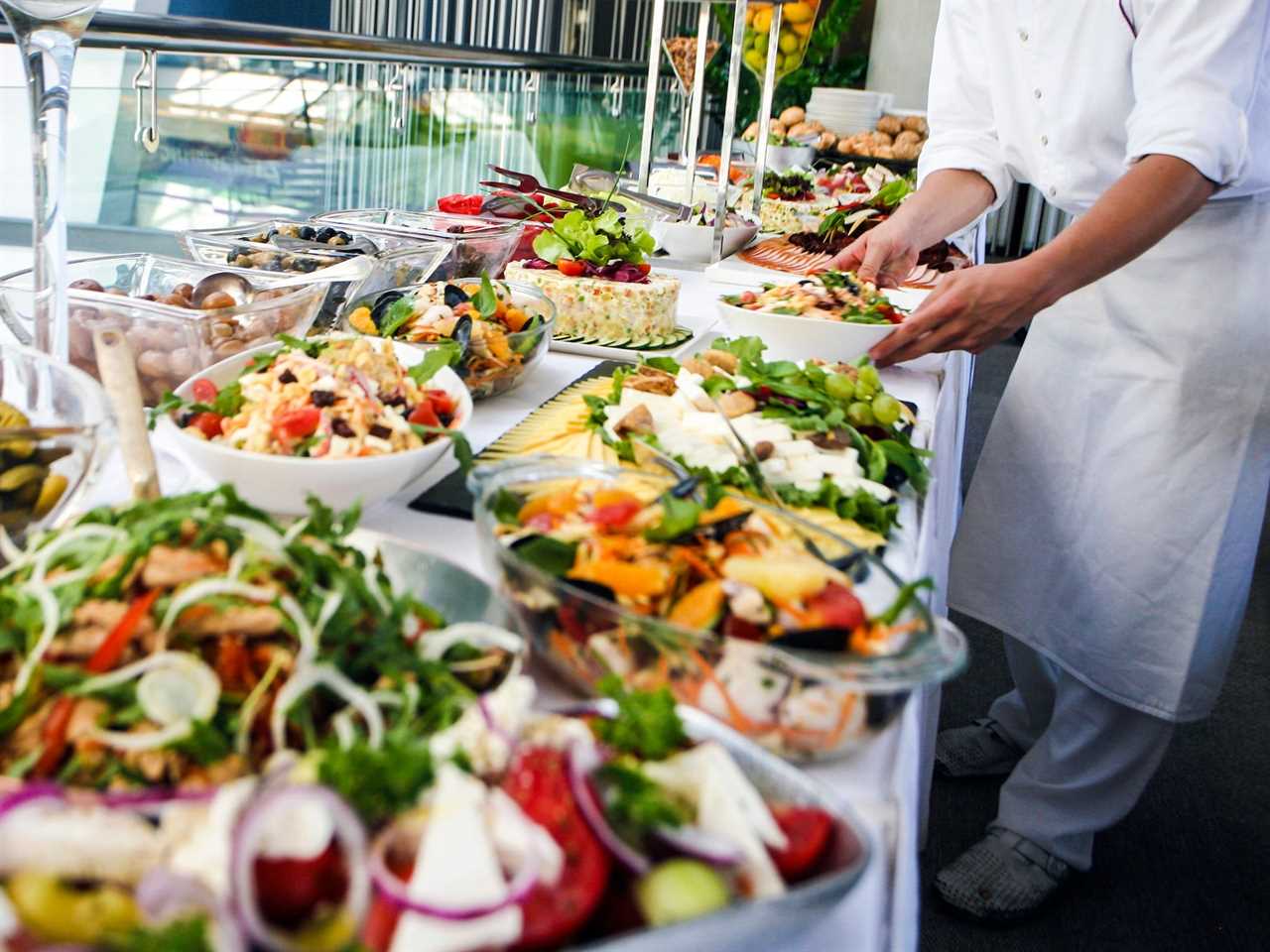 A person putting food down on a buffet table