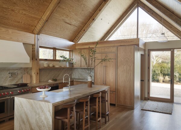 The kitchen is a balance of woods and stone, with marble on the large island and Naica quartzite in a leathered finish on the perimeter counters and backsplash. The stove hood is a custom plaster finish: 