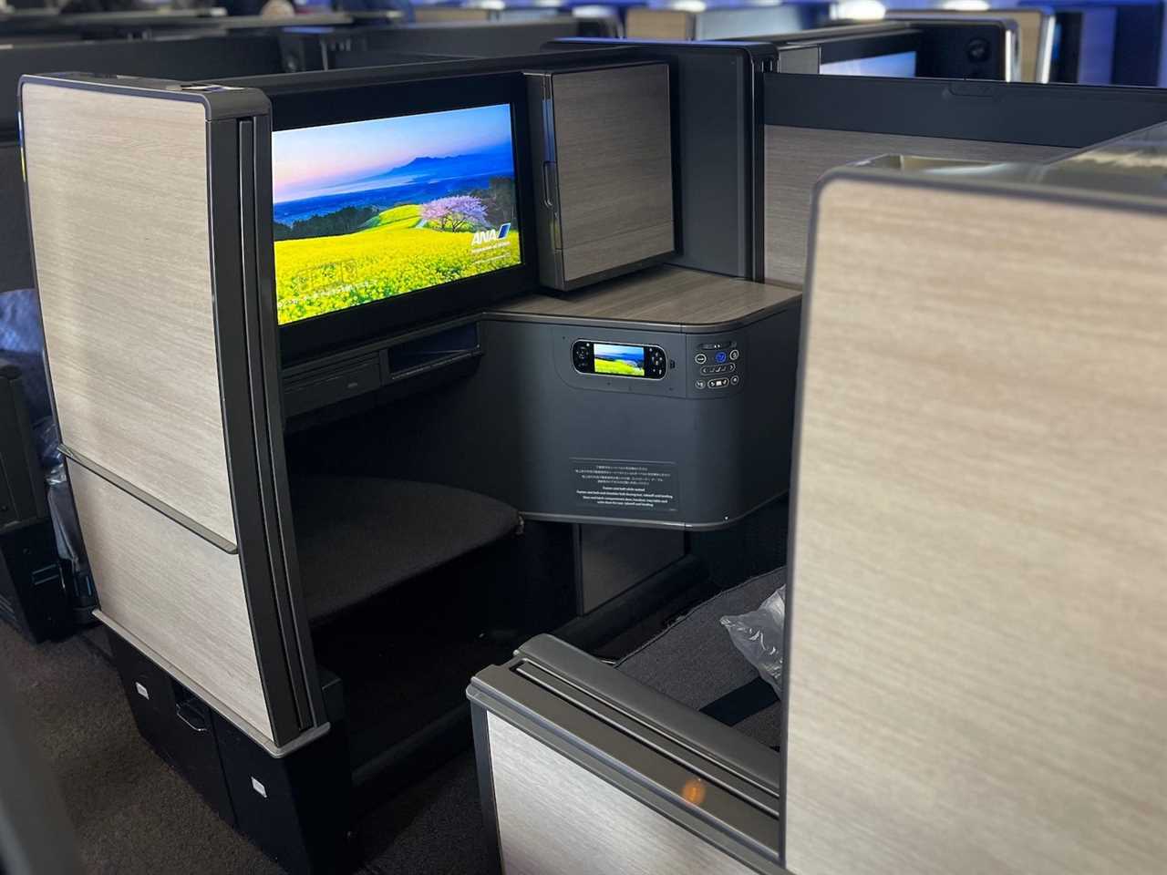 An open "The Room" business class seat with TV in view.