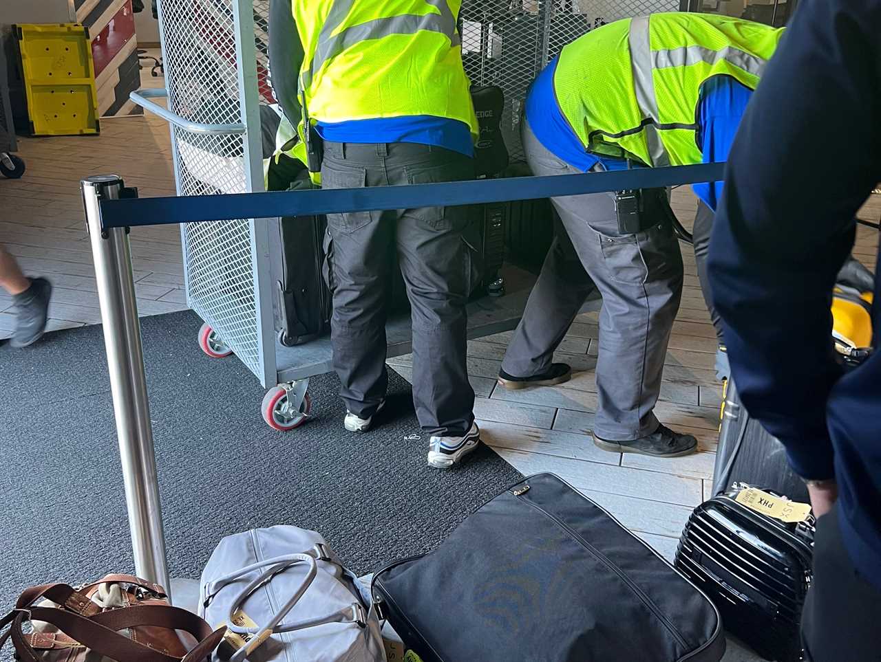 The ground crew in yellow vests unloading luggage.