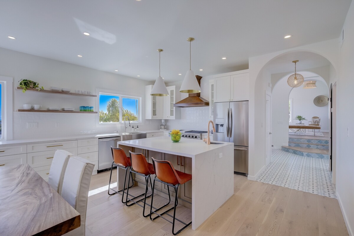 white bright kitchen with new appliances and orange barstools