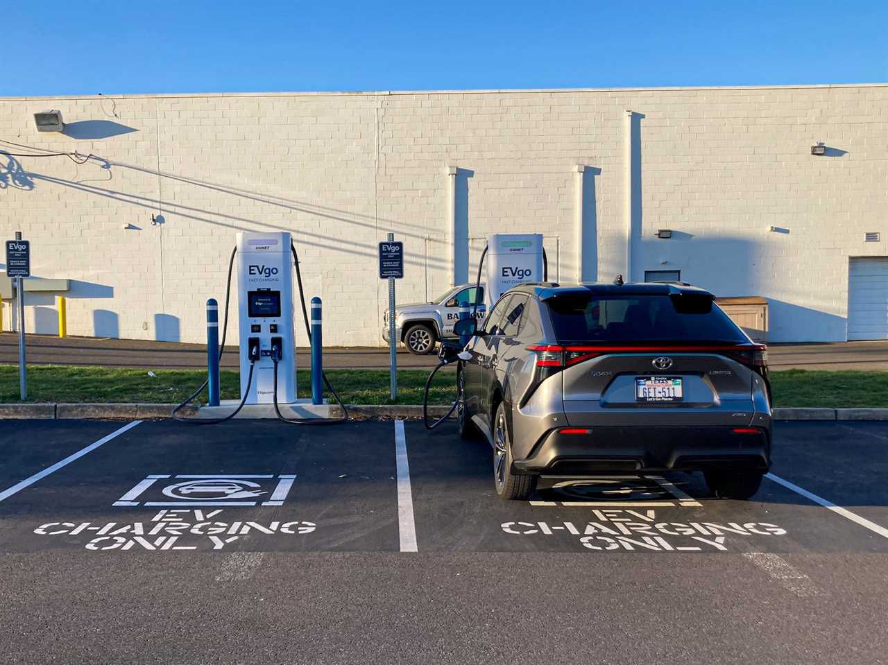 The 2023 Toyota bZ4X AWD Limited electric SUV parked in a parking lot, with a white building and blue skies in the background.