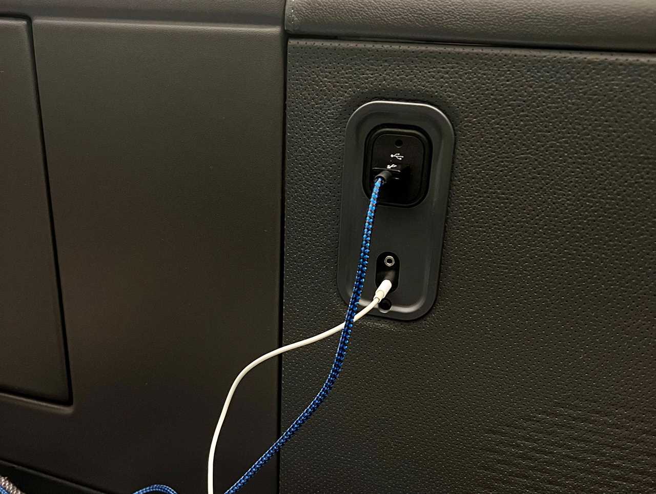 Charging chords plugged into "The Room" business class seat.