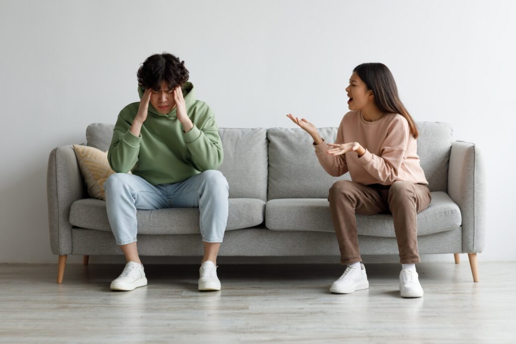 Angry young couple sititng on a couch and fighting