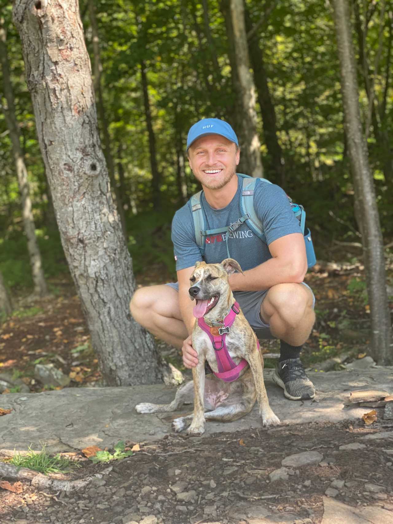 a man stands in the woods with his dog