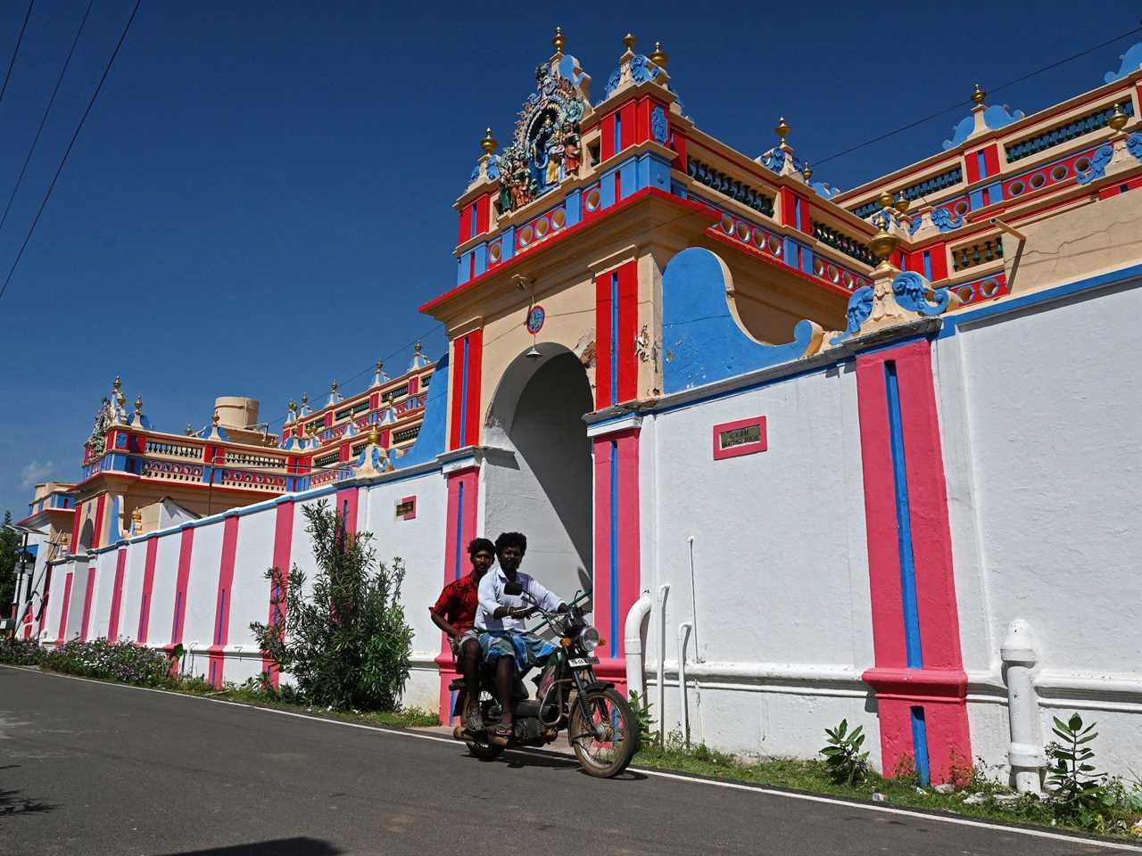 People ride a motorcycle past the newly-renovated CVRM Heritage House in Kanadukathan town in India's Tamil Nadu state in 2021.