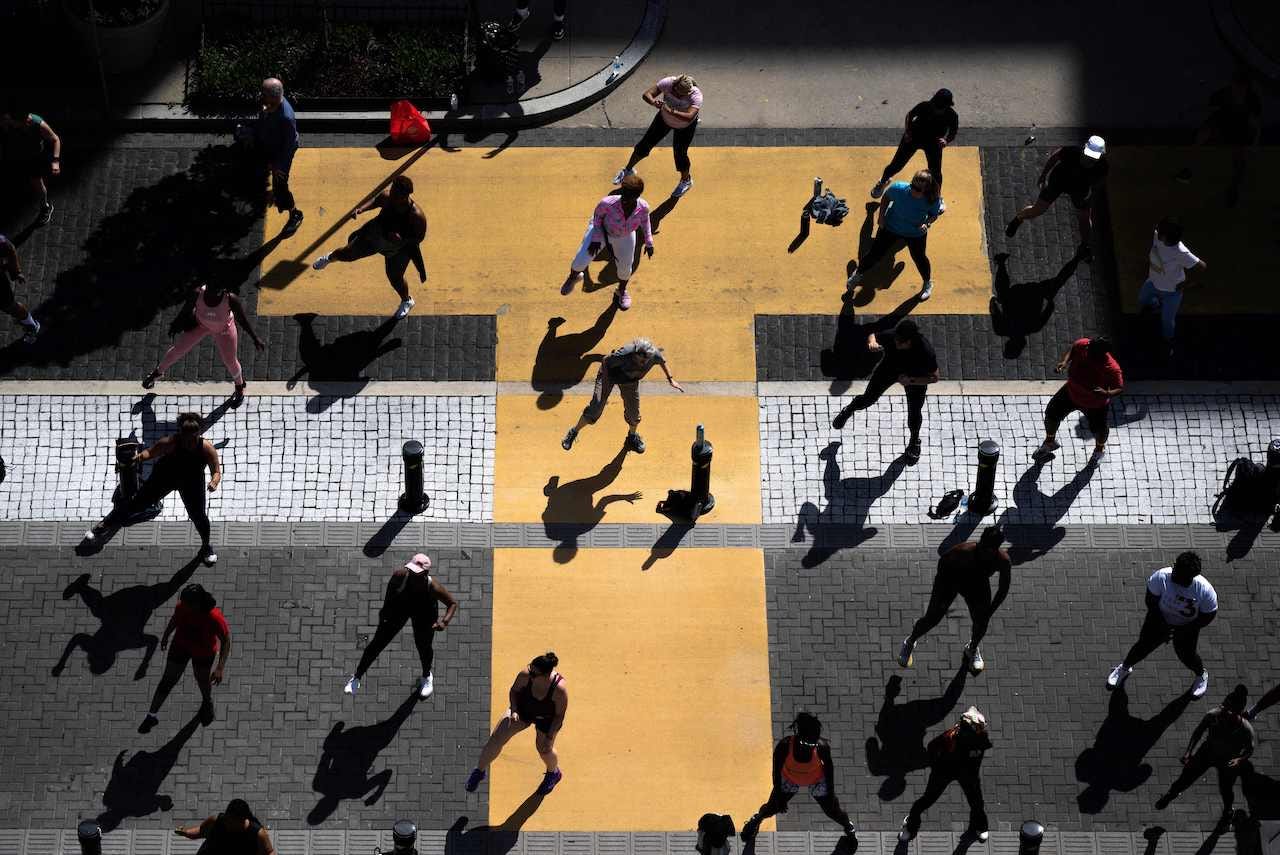 A group of people take part in a morning fitness class on a street near the White House in Washington, DC on April 16, 2023.