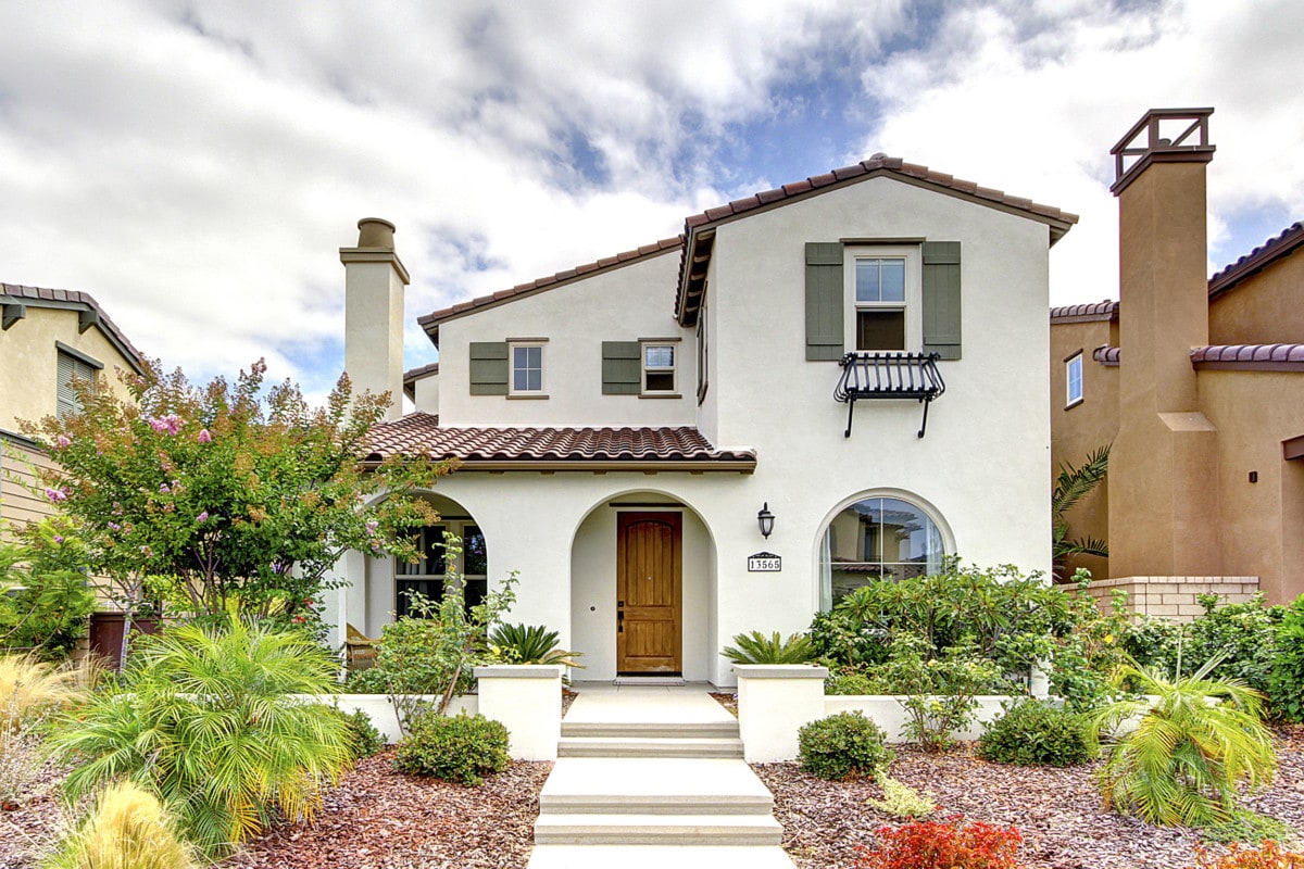 Beige colored stucco home with green shutters